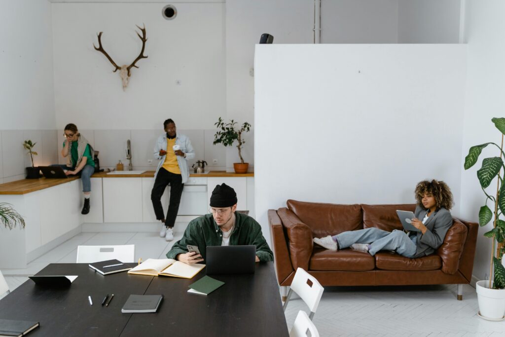 pexels photo 7550530 7550530 Diverse group of adults in a modern office using gadgets like laptops and tablets for work.